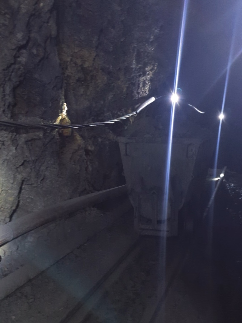 Die Arbeiter laufen zügig mit ihren Wagen aus der Mine. Sie stehen auf die Schienen, damit sie nicht stolpern und umknicken, da der Boden nicht sehr eben ist.