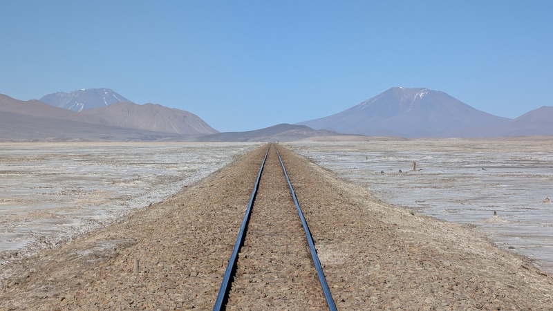 Gleise soweit das Auge reicht. Hier werden heute noch Güter nach Chile und zurück nach Bolivien transportiert. Die Vulkane im Hintergrund sind bereits in Chile.