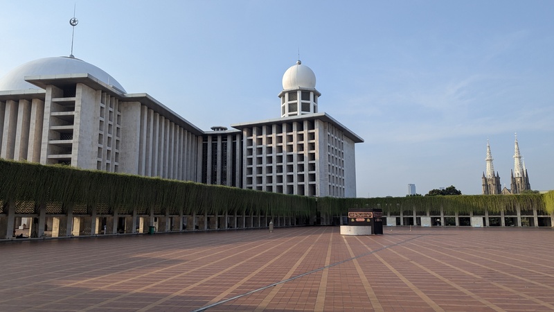 Einer der Aussenplätze der Moschee, welcher ebenso für die Gebete genutzt wird. Im Hintergrund ist die Gereja Kathedrale zu sehen.